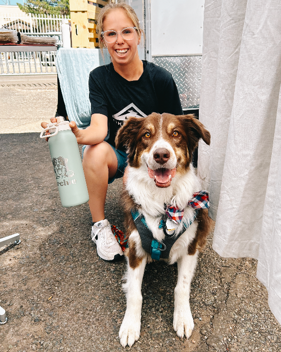 Woman sitting with a dog, holding an engraved water bottle.
